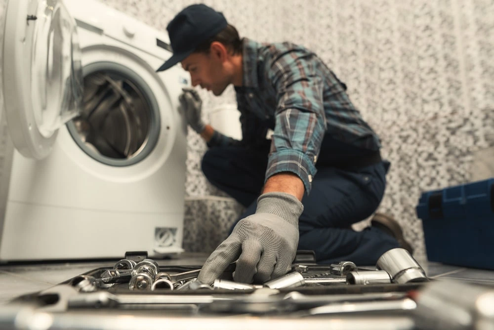 Technician installing a fully automatic washing machine in a Dubai apartment