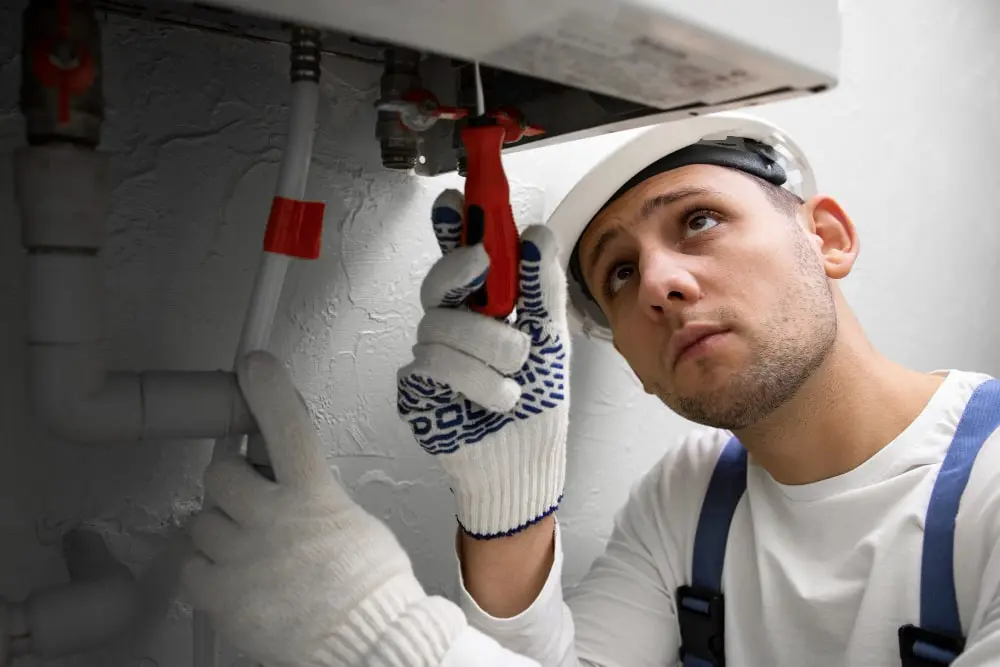 Technician repairing a wall-mounted water heater in a Dubai residential bathroom