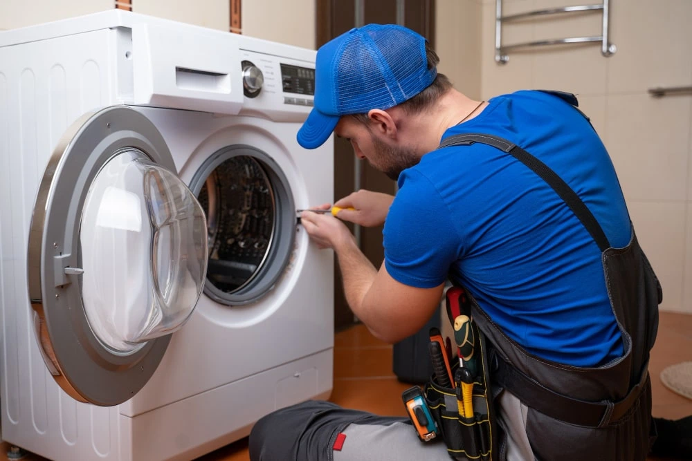 Technician installing a front-load washing machine in a modern Dubai apartment